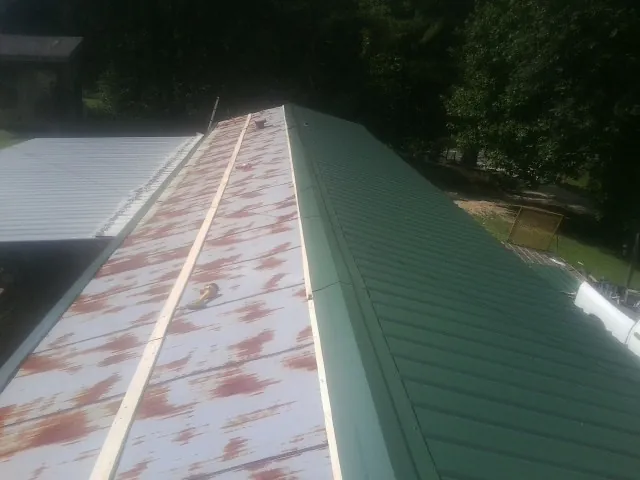 Old rusted panels beside newly installed green metal roofing — Wind Damage Roof Repair by Roofing Brothers in Murray City