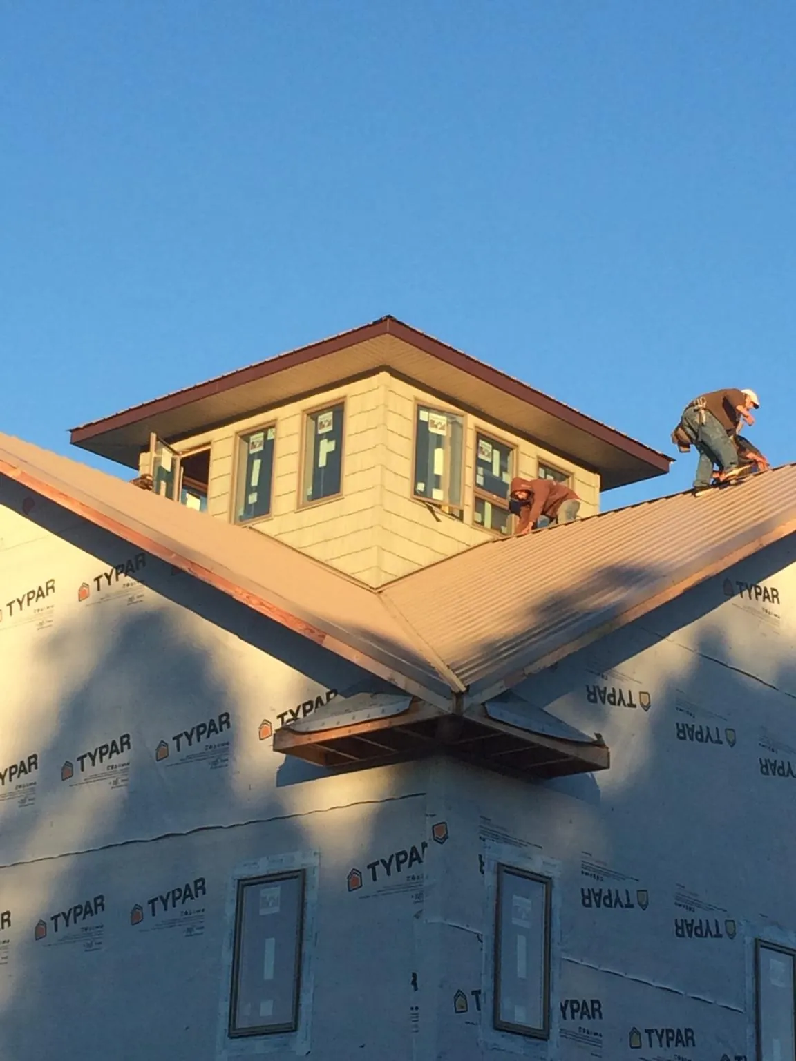 Roofers working around a rooftop cupola on a new metal roof at sunset — Roof Waterproofing in Murray City by Roofing Brothers